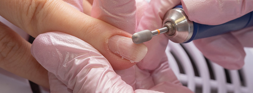 Usuwanie płytki paznokcia za pomocą frezarki stacjonarnej w salonie kosmetycznym